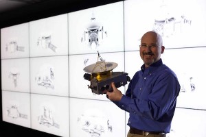 Con un modelo a escala de la sonda New Horizons en sus manos, Chris Hersman explica cómo la imaginación de los científicos se encuentra con las limitaciones de la ingeniería para recrear este diseño de la aeronave. |  National Geographic Channels/Harriet Bailey).